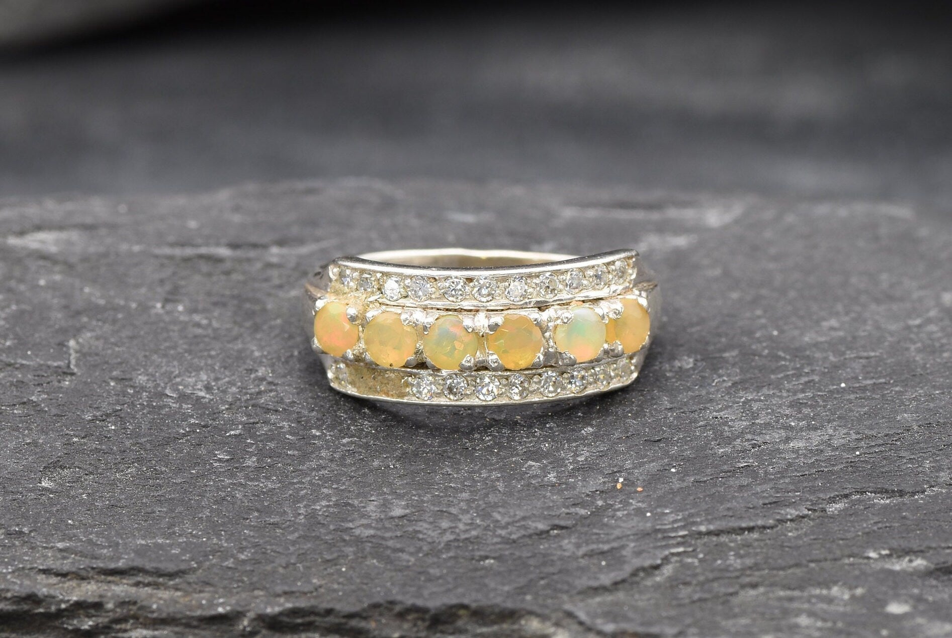 Opal Row Half Eternity Wide Ring in sterling silver featuring natural fire opals with flashes of fire colors, accented by CZ pave for a bold jewelry style. A meaningful October birthstone piece symbolizing balance and inspiration, making it a treasured gift idea. Perfect for weddings, anniversaries, cocktail events, and elegant evening occasions.