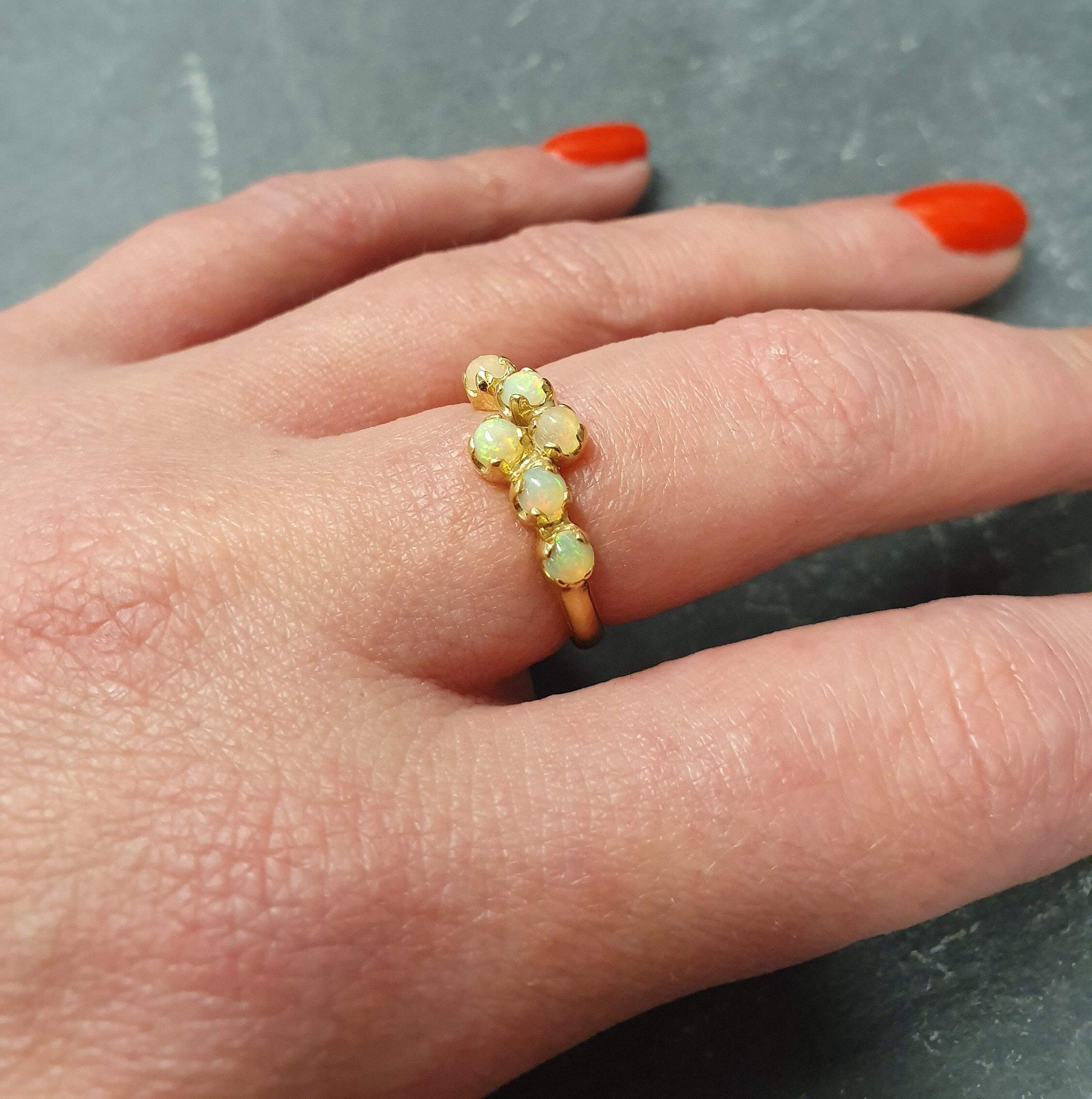 Flower Opal Ring styled on middle finger with bright red nails, featuring a six-stone bypass design, offering radiant flashes of fire colors, a meaningful October birthstone gift, perfect for night parties and celebrations.
