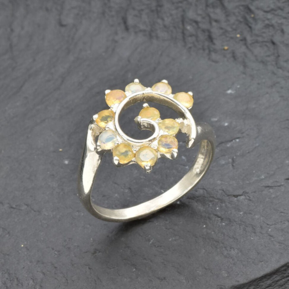 Opal Spiral Ring in sterling silver designed as a sunburst swirl statement jewelry piece offering radiant flashes of fire colors and boho charm, believed to inspire creativity and positivity, making it a thoughtful October birthstone gift idea. Perfect to wear at weddings, parties, and special occasions for a vibrant standout look.