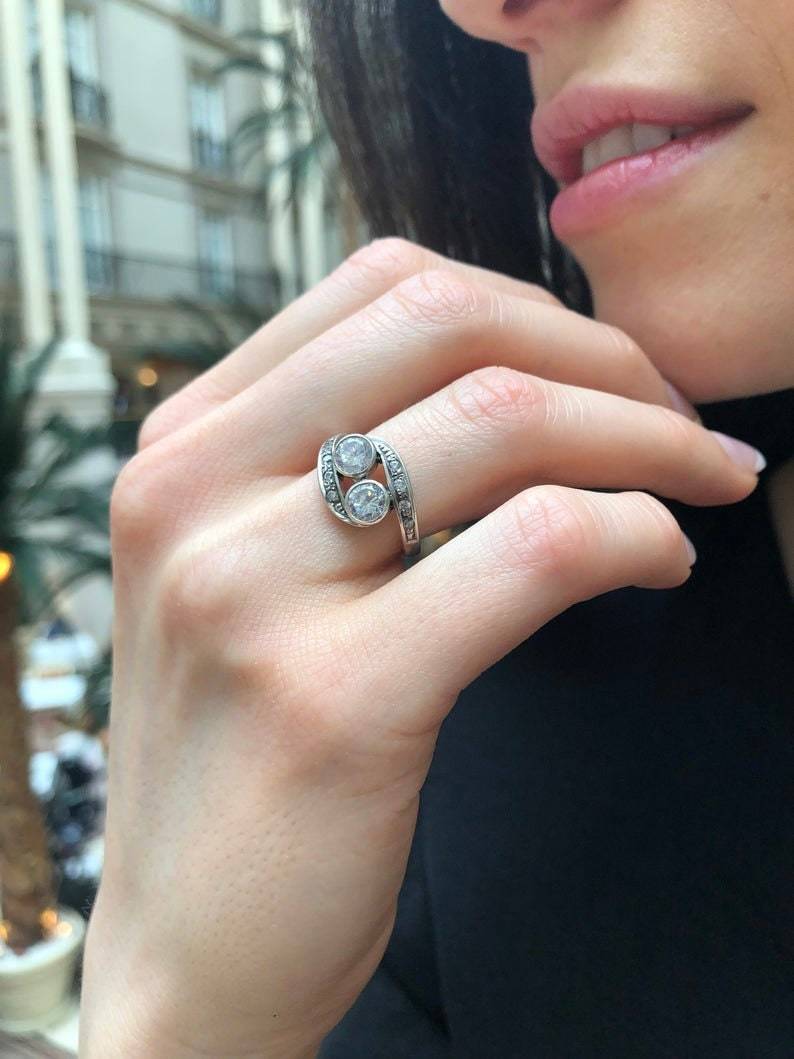 Opal Two-Stone Bypass Wave Ring worn with a black V-neck dress and paired with matching earrings, showcasing the opal’s fire colors and wave bypass design accented by CZ pave. A sophisticated October birthstone accessory, ideal for gala dinners, cocktail events, and festive celebrations.