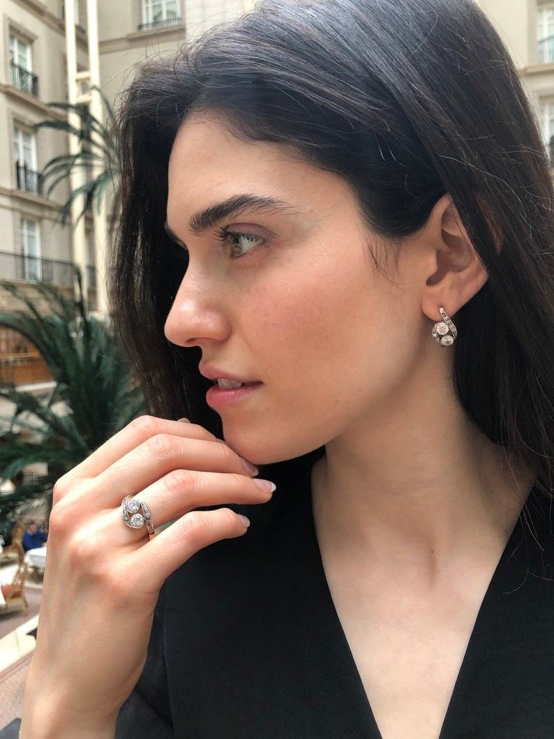 Opal Two-Stone Bypass Wave Ring worn with a black V-neck dress and paired with matching earrings, showcasing the opal’s fire colors and wave bypass design accented by CZ pave. A sophisticated October birthstone accessory, ideal for gala dinners, cocktail events, and festive celebrations.