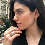 Opal Two-Stone Bypass Wave Ring worn with a black V-neck dress and paired with matching earrings, showcasing the opal’s fire colors and wave bypass design accented by CZ pave. A sophisticated October birthstone accessory, ideal for gala dinners, cocktail events, and festive celebrations.