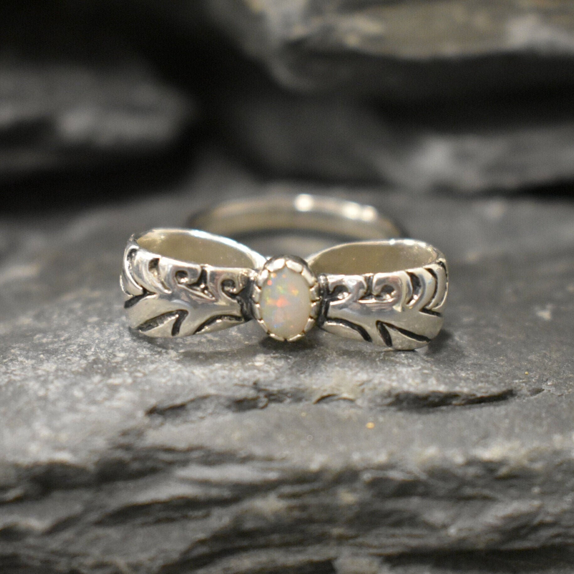 Opal ring in handcrafted solid silver with a ribbon bow style band and white cabochon showing flashes of fire color, a statement design that brightens the hand. Brings creative spark and calm confidence while adding a luminous white accent to any look. A thoughtful October birthstone gift idea for someone special.
Wear to weddings, anniversaries, engagements, date nights, office parties, graduations, and holiday gatherings.