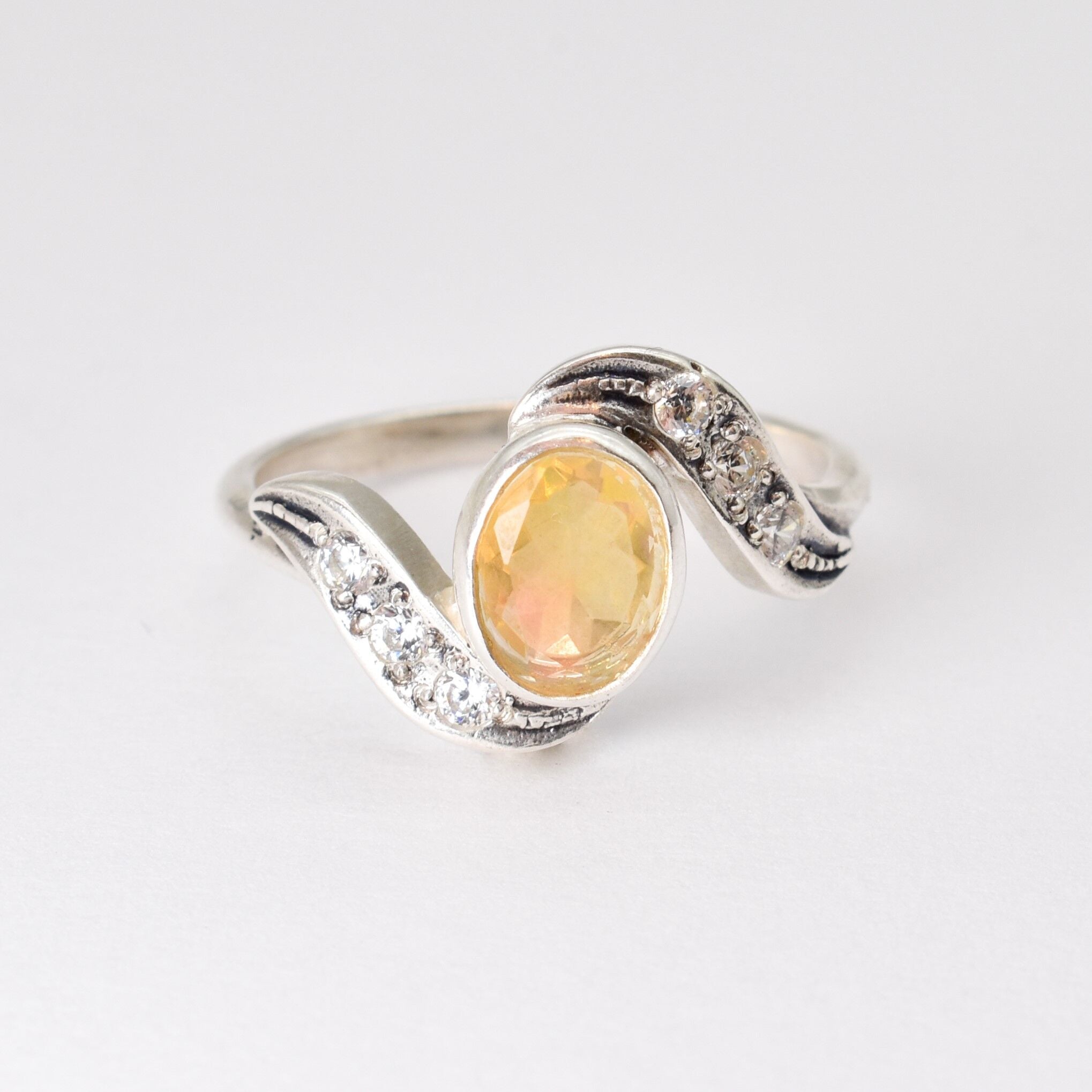 Fire Opal bezel wave ring with CZ pave in sterling silver, featuring flashes of rainbow fire colors, designed in a dainty jewelry style symbolizing passion and hope, a powerful October birthstone gift idea for engagements, anniversaries, and special occasions.
