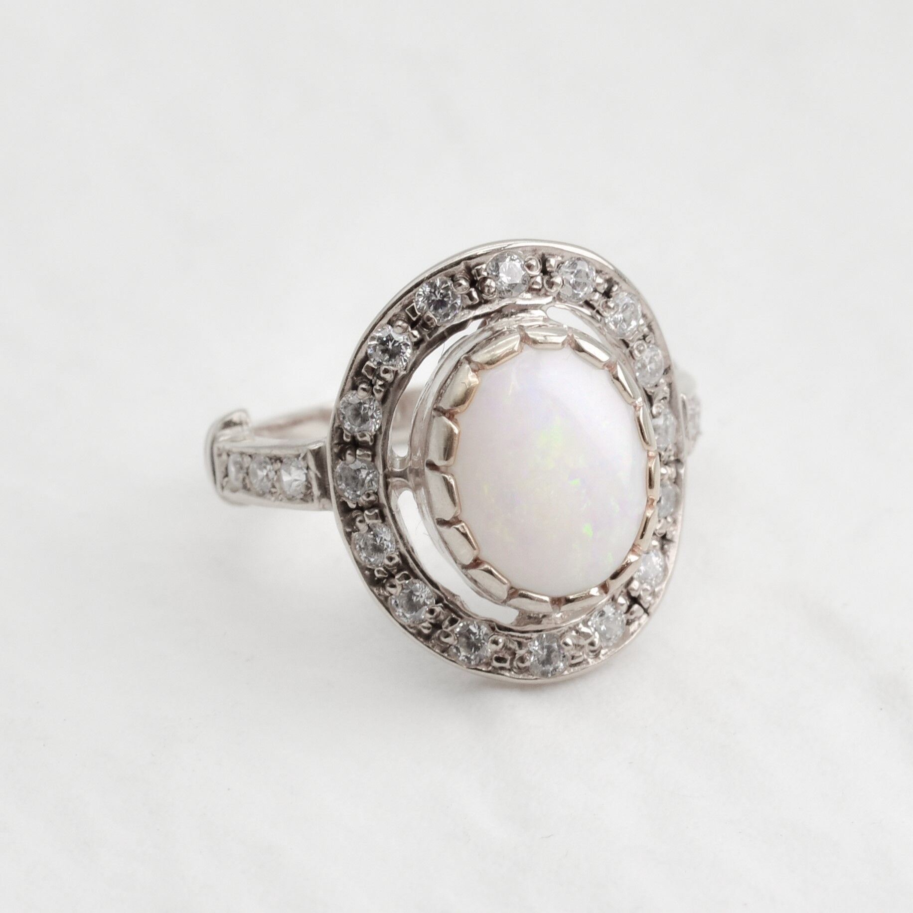 Australian Opal statement ring in silver with halo of CZ diamonds, featuring an oval cabochon gemstone, ideal for glamorous statement style, believed to inspire creativity and love, a perfect October birthstone gift for anniversaries, engagements, and elegant celebrations.