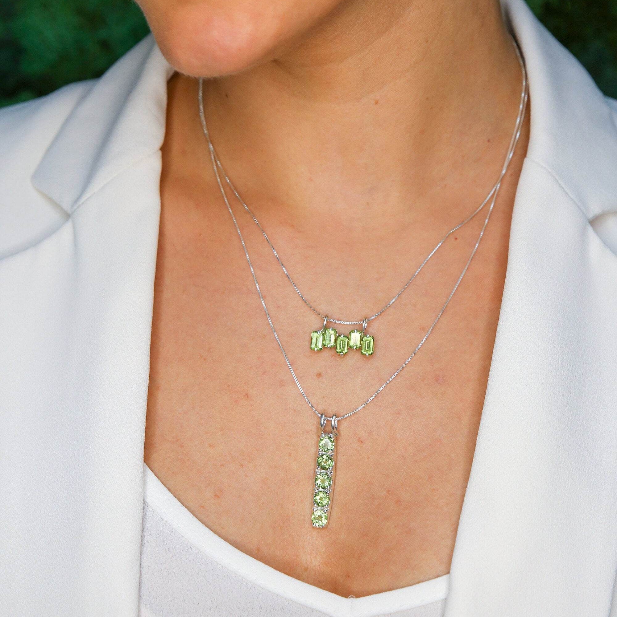 Peridot pendant necklace styled with a white V-neck top and white blazer, perfect for professional and elegant occasions, adding a fresh and vibrant touch to the outfit.