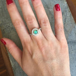 Emerald Halo Ring worn on the index finger with glossy red nails, sterling silver band accented with CZ stones highlighting the central opal’s flashes of fire colors. A chic October Birthstone design perfect for evening parties, romantic dinners, and wedding receptions.