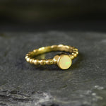 Ethiopian Opal Bezel Promise Ring in gold featuring a round diamond cut stone set in a bubble tennis band design, a stylish jewelry piece radiating flashes of fire colors while symbolizing love and commitment, making it a meaningful October birthstone gift idea. Perfect for engagements, anniversaries, and elegant evening occasions to showcase understated brilliance.