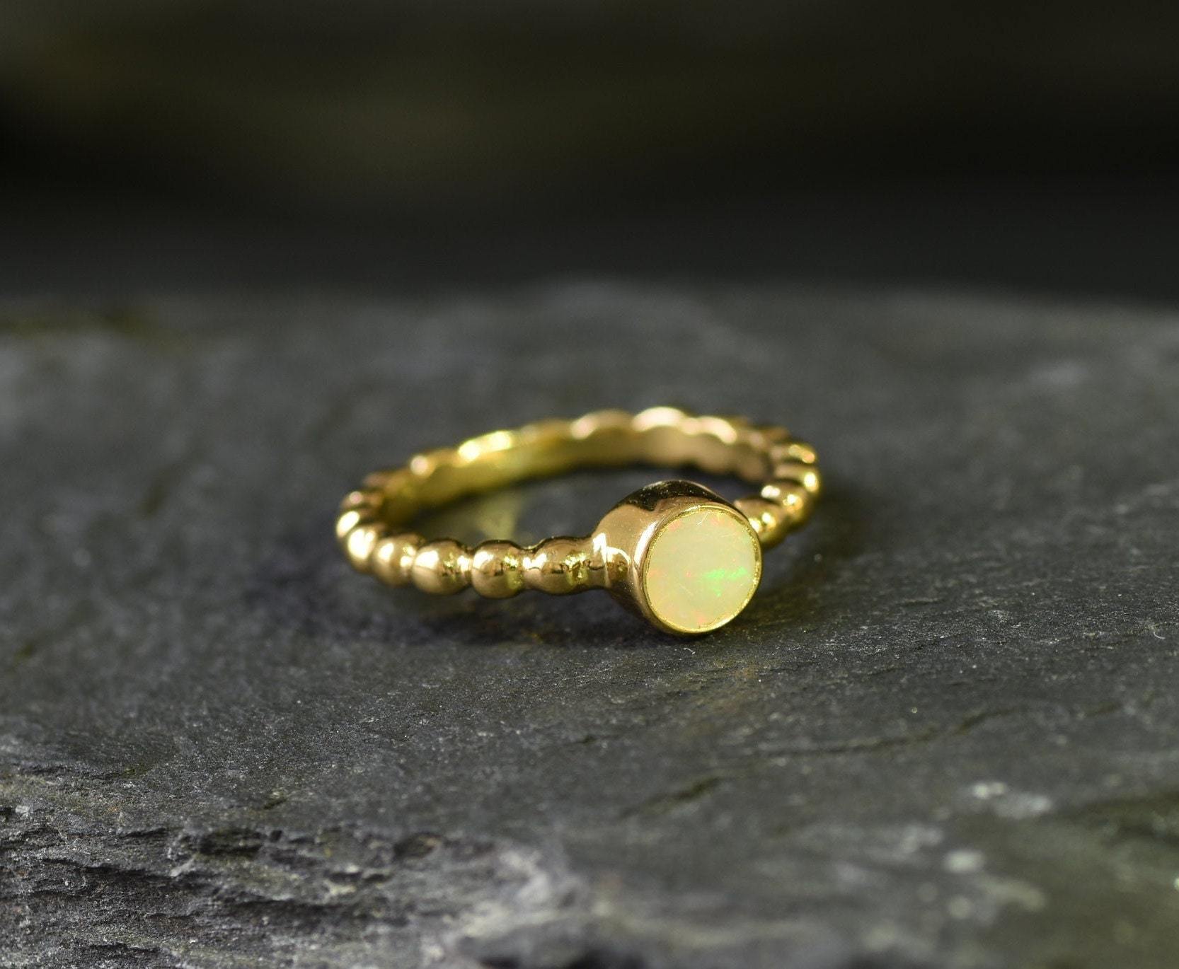 Ethiopian Opal Bezel Promise Ring in gold featuring a round diamond cut stone set in a bubble tennis band design, a stylish jewelry piece radiating flashes of fire colors while symbolizing love and commitment, making it a meaningful October birthstone gift idea. Perfect for engagements, anniversaries, and elegant evening occasions to showcase understated brilliance.