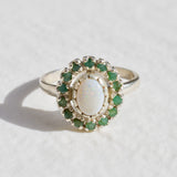 Australian Opal and Colombian Emerald halo ring in sterling silver with oval cabochon opal and diamond-cut emeralds, perfect for statement elegance, believed to inspire love and prosperity, an ideal October and May birthstone gift for weddings, anniversaries, and special celebrations.
