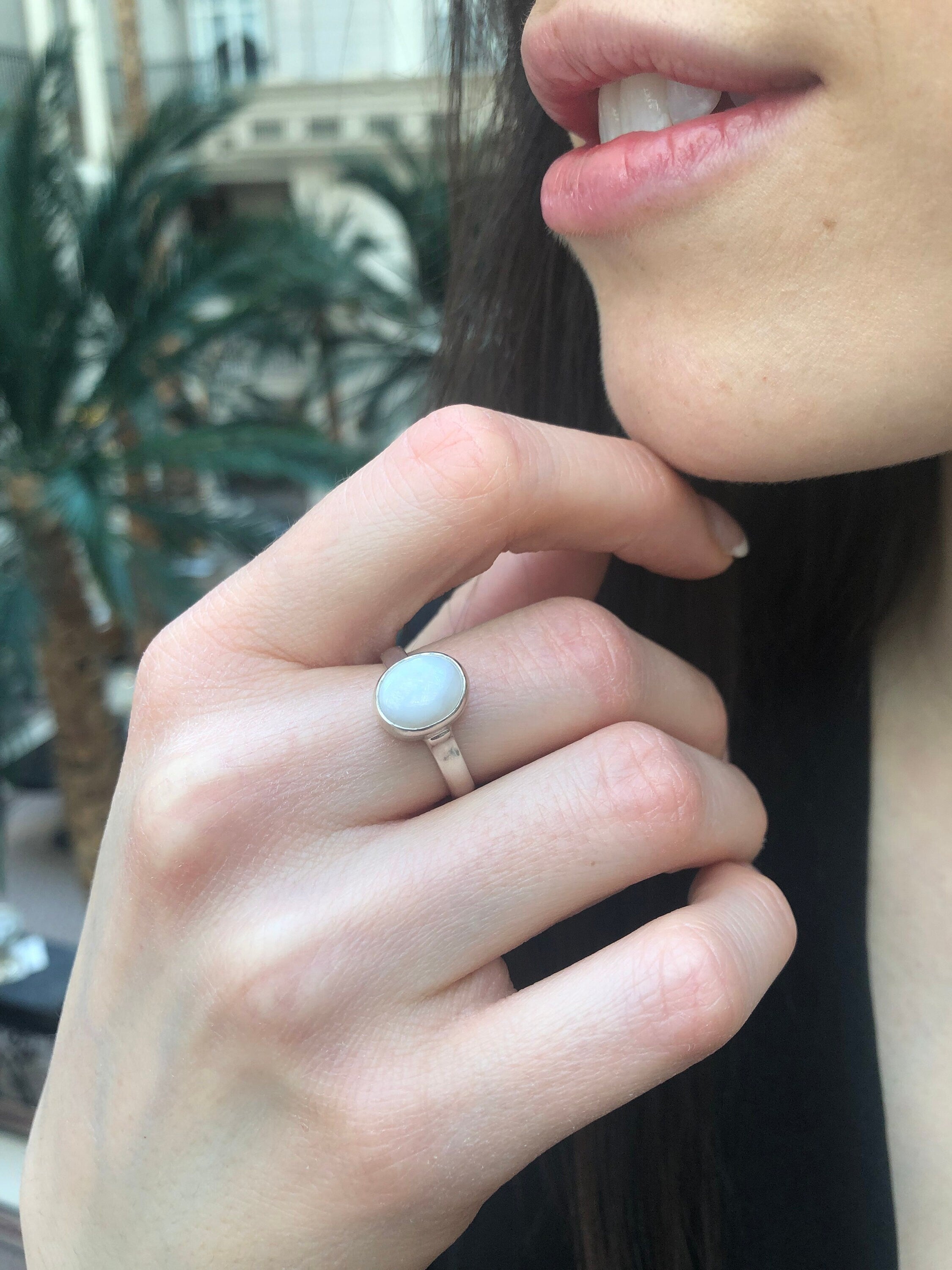 White Opal Bezel Ring paired with sleek hair and minimalist accessories. Jewelry style is timeless solitaire design with a cabochon stone that glows with fire colors and rainbow flashes. Brings emotional balance, clarity, and inspiration. A thoughtful October birthstone gift for anniversaries or birthdays. Perfect for formal dinners, weddings, and everyday elegance.