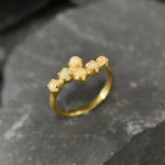 Ethiopian Opal Bypass Ring in gold with six cabochon stones aligned in a curved wrap setting, a stylish jewelry design that radiates flashes of fire colors and adds a modern edge, making it a thoughtful October birthstone gift idea. Perfect to wear at weddings, cocktail parties, and romantic dinners for a bold yet refined look.