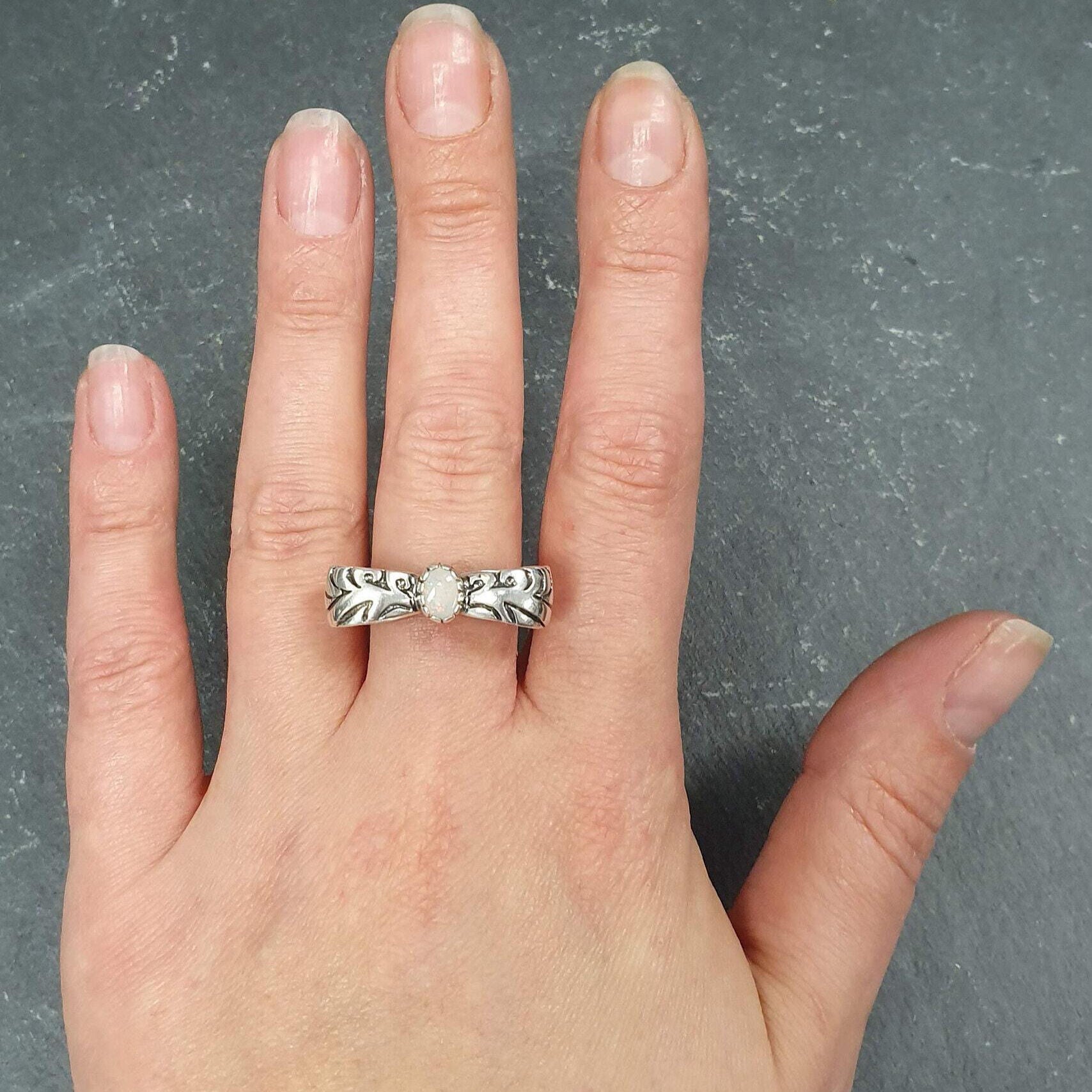 Opal ring in handcrafted solid silver with a ribbon bow style band and white cabochon showing flashes of fire color, a statement design that brightens the hand. Brings creative spark and calm confidence while adding a luminous white accent to any look. A thoughtful October birthstone gift idea for someone special.
Wear to weddings, anniversaries, engagements, date nights, office parties, graduations, and holiday gatherings.