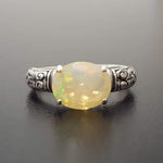 Ethiopian Fire Opal Sterling Silver Ring featuring a horizontal oval cut with a secure 4-prong setting. The engraved ornament band adds vintage charm, while the opal displays brilliant flashes of fire colors. A timeless October birthstone ring, perfect for birthdays, anniversaries, weddings, and milestone celebrations.