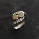 Two-Stone Opal Bypass Wave Ring in sterling silver showcasing cabochon-cut opals with flashes of fire colors and CZ pave accents for an elegant jewelry style. Known for enhancing emotional clarity and balance, this October birthstone ring makes a thoughtful and meaningful gift idea. Perfect for anniversaries, weddings, cocktail events, and celebratory occasions where sophistication shines.