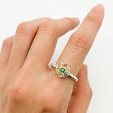 Opal Emerald Ring styled with bare nails on a natural hand. Jewelry style highlights a vintage floral setting with a sterling silver band. Offers harmony, protection and inspiration. Makes a thoughtful birthstone jewelry gift for loved ones. Worn beautifully at garden parties, engagement events, or weekend outings.