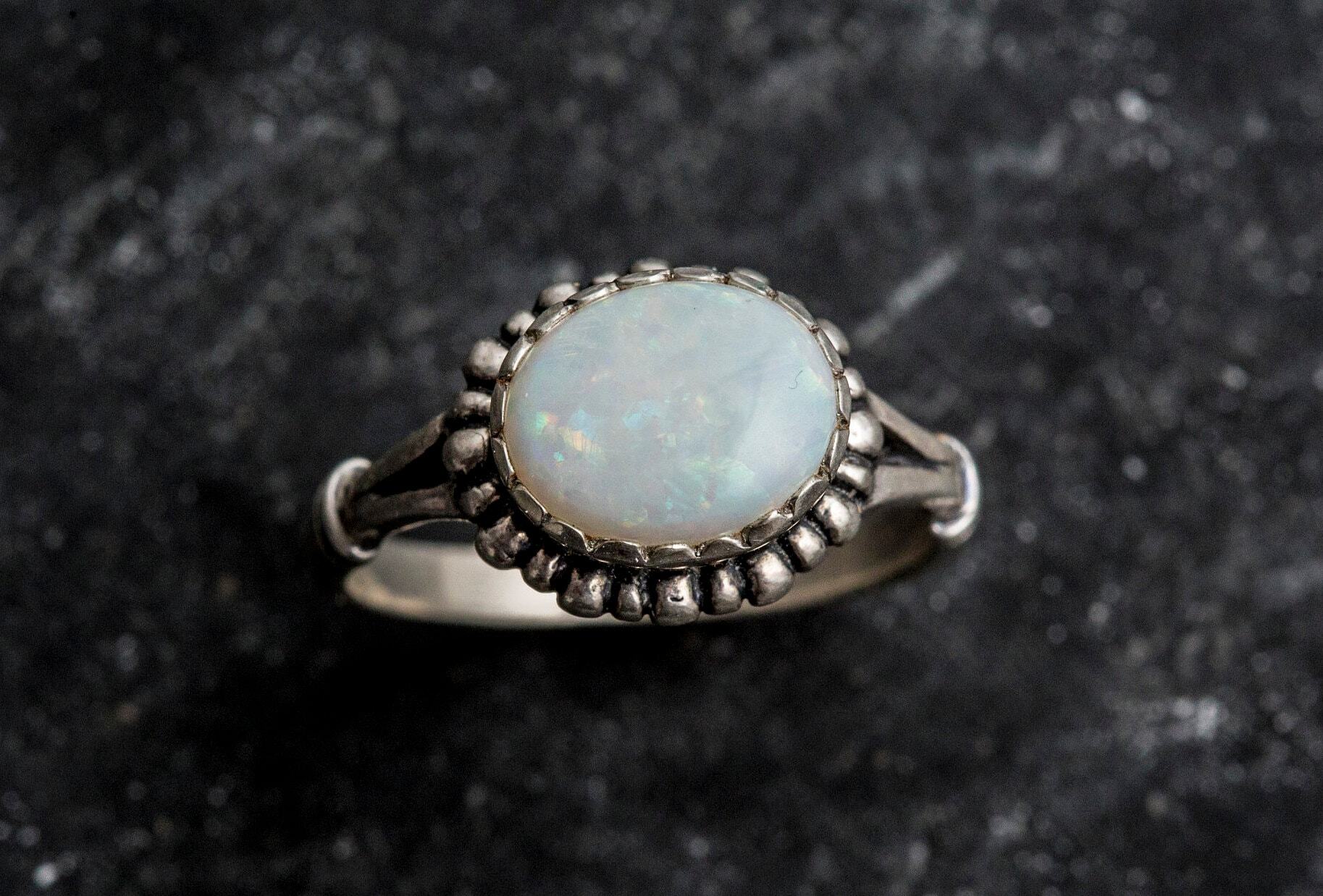 Australian Opal Ring in sterling silver with a horizontal oval cabochon design, white stone showing flashes of fire colors, delicate jewelry style for everyday elegance, meaningful October birthstone gift idea. Perfect for weddings, anniversaries, cocktail parties, and milestone events.