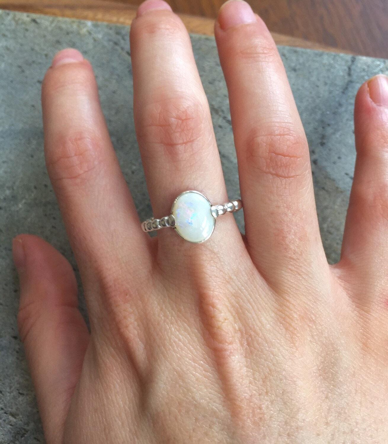 White Opal Bubble Band Ring worn on middle finger with bare nails, great for promoting emotional balance and creativity, suited for casual outings or art events.