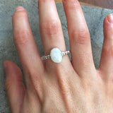 White Opal Bubble Band Ring worn on middle finger with bare nails, great for promoting emotional balance and creativity, suited for casual outings or art events.