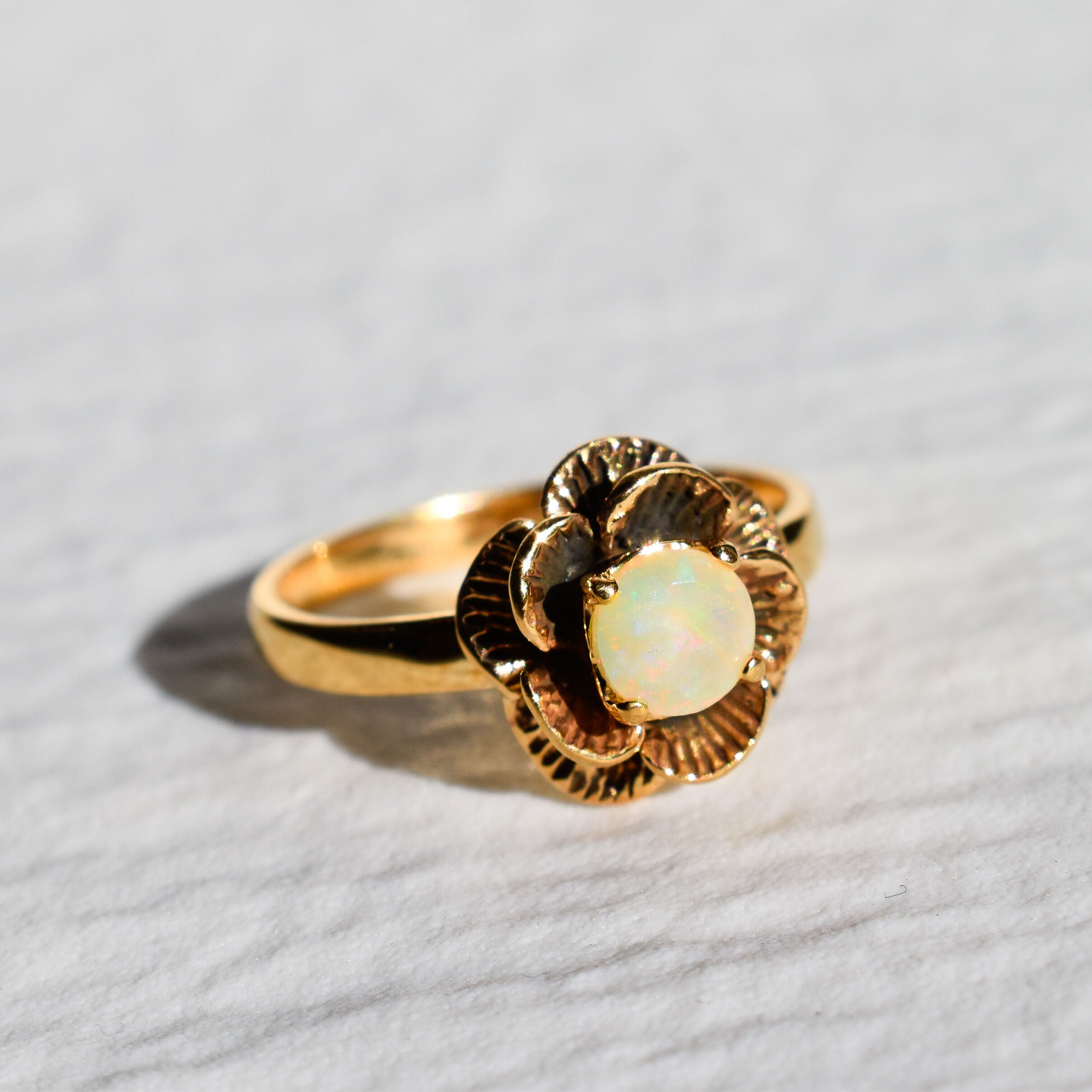 Vintage Fire Opal flower ring with a rose inspired artisan design in gold. The daisy style petals frame a round opal center for a floral and feminine look. Opal is believed to bring hope, creativity and emotional balance, making it a meaningful October birthstone gift. Perfect for weddings, anniversaries, special celebrations and romantic events.
