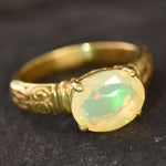 Ethiopian Fire Opal Gold Ring featuring a horizontal oval cut with a secure 4-prong setting. The engraved ornament band adds vintage charm, while the opal displays brilliant flashes of fire colors. A timeless October birthstone ring, perfect for birthdays, anniversaries, weddings, and milestone celebrations.