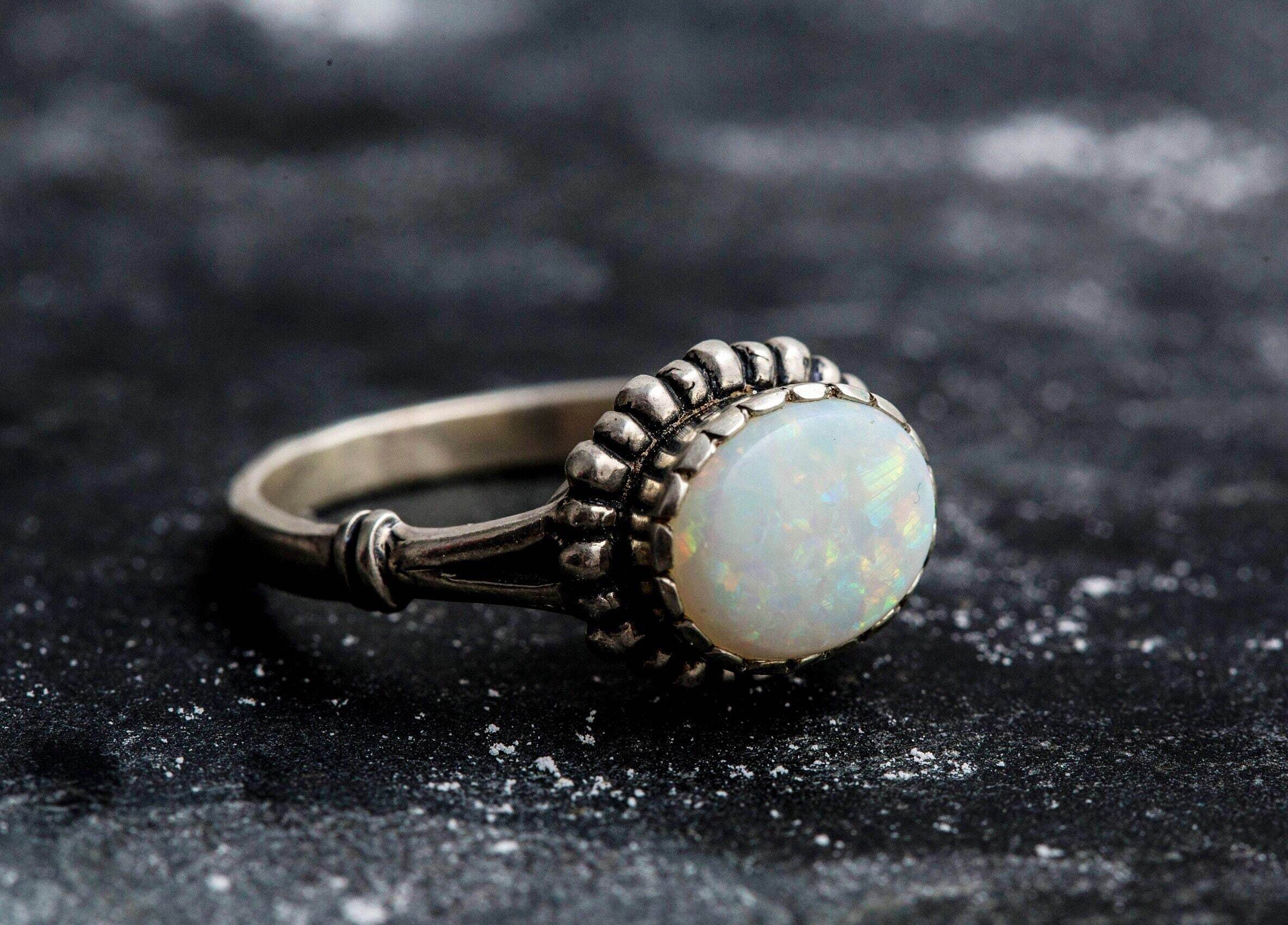 Australian Opal Ring in sterling silver with a horizontal oval cabochon design, white stone showing flashes of fire colors, delicate jewelry style for everyday elegance, meaningful October birthstone gift idea. Perfect for weddings, anniversaries, cocktail parties, and milestone events.