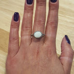 White Fire Opal Ring worn on middle finger with purple  nails, horizontal cabochon design shimmering with flashes of fire colors, meaningful October birthstone jewelry. Perfect for weddings, anniversaries, and elegant celebrations.