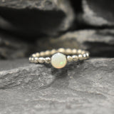Australian White Opal bezel bubble band ring in sterling silver with round cabochon cut and flashes of fire colors, a chic jewelry style perfect for stacking and minimal elegance. Offers the benefit of a secure bezel set design with playful bubble band details, making it an ideal October birthstone gift. Perfect for birthdays, anniversaries, weddings, or everyday wear.