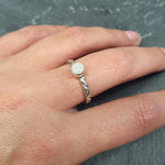 White Opal Solitaire Ring worn on ring finger with nude nails, twisted silver band highlighting flashes of fire colors, perfect as an October birthstone for balance and charm, suitable for date nights, birthdays, and special celebrations.