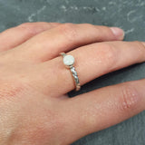 White Opal Solitaire Ring worn on ring finger with nude nails, twisted silver band highlighting flashes of fire colors, perfect as an October birthstone for balance and charm, suitable for date nights, birthdays, and special celebrations.