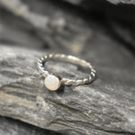 White Opal bezel solitaire ring with round cut stone and twisted band in sterling silver, a timeless jewelry style that highlights flashes of fire colors and durability. Offers the benefit of a secure bezel setting with a refined solitaire look, making it a meaningful October birthstone gift idea. Perfect for birthdays, anniversaries, engagements, and daily wear events.