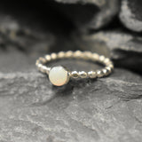 Australian White Opal bezel bubble band ring in sterling silver with round cabochon cut and flashes of fire colors, a chic jewelry style perfect for stacking and minimal elegance. Offers the benefit of a secure bezel set design with playful bubble band details, making it an ideal October birthstone gift. Perfect for birthdays, anniversaries, weddings, or everyday wear.