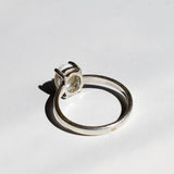 White Opal solitaire ring in sterling silver showcasing flashes of rainbow colors, dainty jewelry style perfect for daily elegance, believed to bring inspiration and emotional balance, a meaningful October birthstone gift idea for anniversaries, engagements, and weddings.