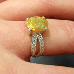 Ethiopian Opal Oval Ring in sterling silver with a 4 prong setting and split shank design. Jewelry style features a CZ pave band that adds brilliance around the opal gemstone, glowing with flashes of fire colors. Opal is known for inspiring creativity, passion, and emotional balance. A meaningful October birthstone gift for birthdays, anniversaries, and special milestones. Perfect to wear at weddings, evening dinners, formal events, and cocktail parties.