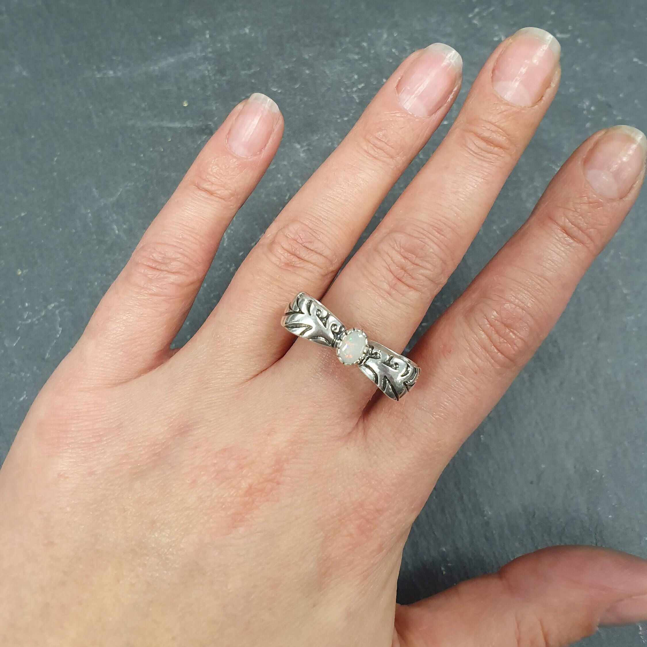 Opal ring in handcrafted solid silver with a ribbon bow style band and white cabochon showing flashes of fire color, a statement design that brightens the hand. Brings creative spark and calm confidence while adding a luminous white accent to any look. A thoughtful October birthstone gift idea for someone special.
Wear to weddings, anniversaries, engagements, date nights, office parties, graduations, and holiday gatherings.