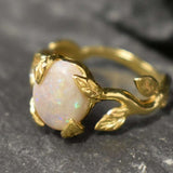 White Opal cabochon vine and leaf ring crafted in gold, featuring a nature-inspired design with flashes of fire colors. The durable vine-style band offers elegance and uniqueness while remaining comfortable for daily wear. As the October Birthstone, White Opal makes a thoughtful gift for birthdays, anniversaries, and nature lovers. Perfect to wear at weddings, outdoor celebrations, and festive gatherings.