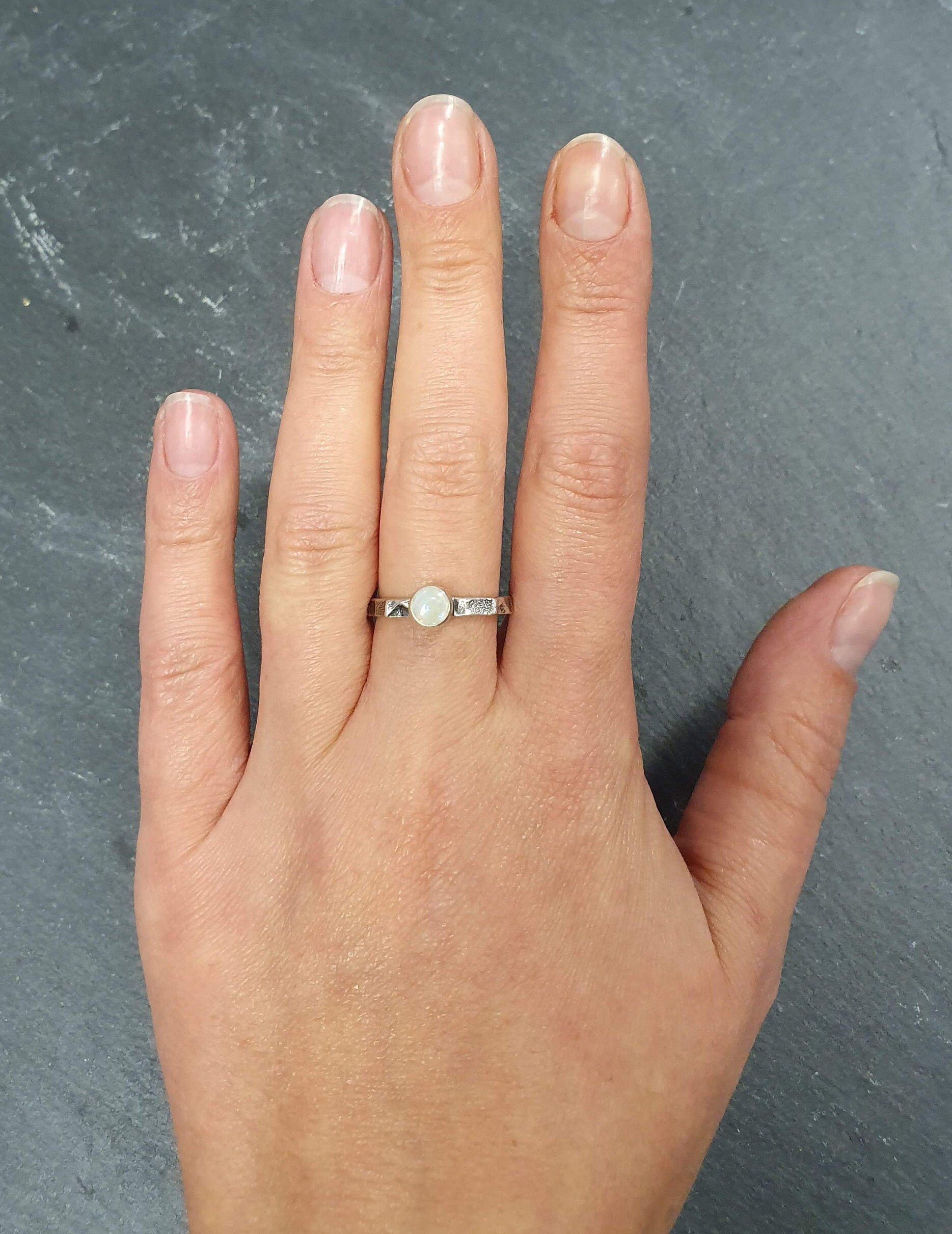 White Opal Ring worn on middle finger with nude nails paired with hammered silver band. Brings creativity and calmness, a meaningful October birthstone gift. Perfect for dinners, anniversaries and special celebrations.