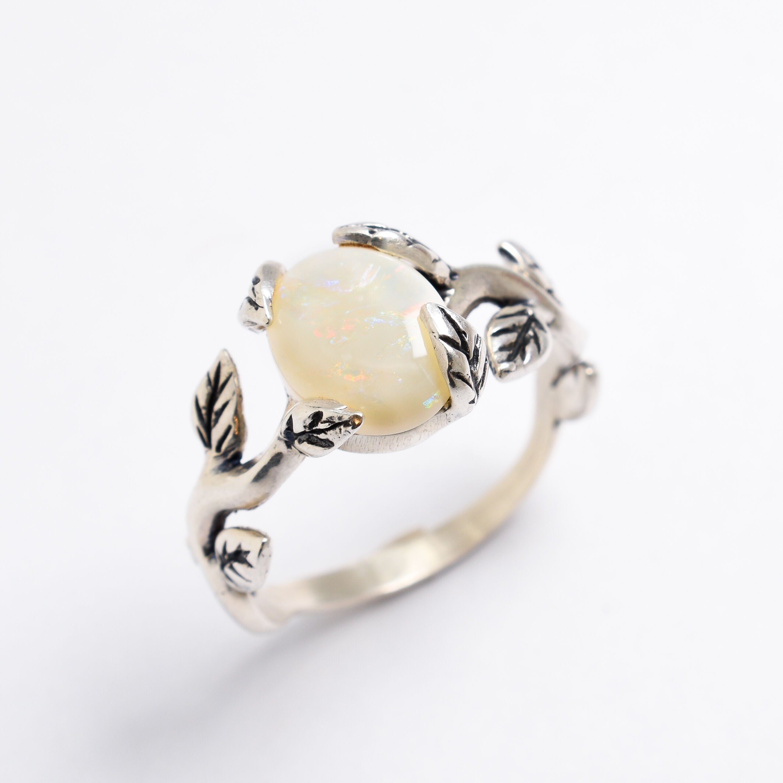 White Opal cabochon vine and leaf ring crafted in solid 925 sterling silver, featuring a nature-inspired design with flashes of fire colors. The durable vine-style band offers elegance and uniqueness while remaining comfortable for daily wear. As the October Birthstone, White Opal makes a thoughtful gift for birthdays, anniversaries, and nature lovers. Perfect to wear at weddings, outdoor celebrations, and festive gatherings.
