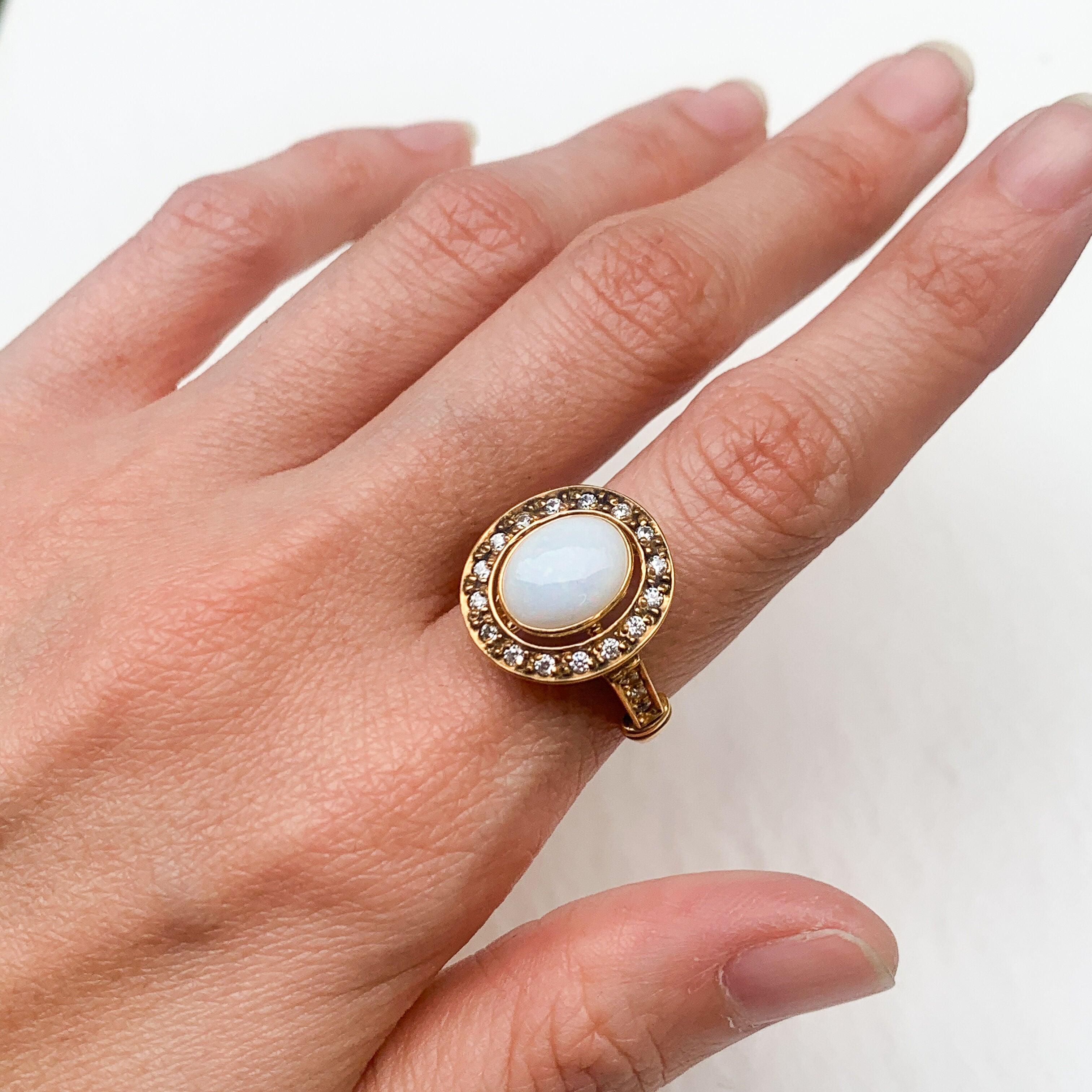 Natural Opal ring in gold with a halo of sparkling diamonds, featuring a cabochon cut gemstone for an elegant and timeless style. Known for promoting creativity and emotional balance, Opal is the October birthstone and makes a thoughtful gift for birthdays, anniversaries, weddings, or milestone celebrations.