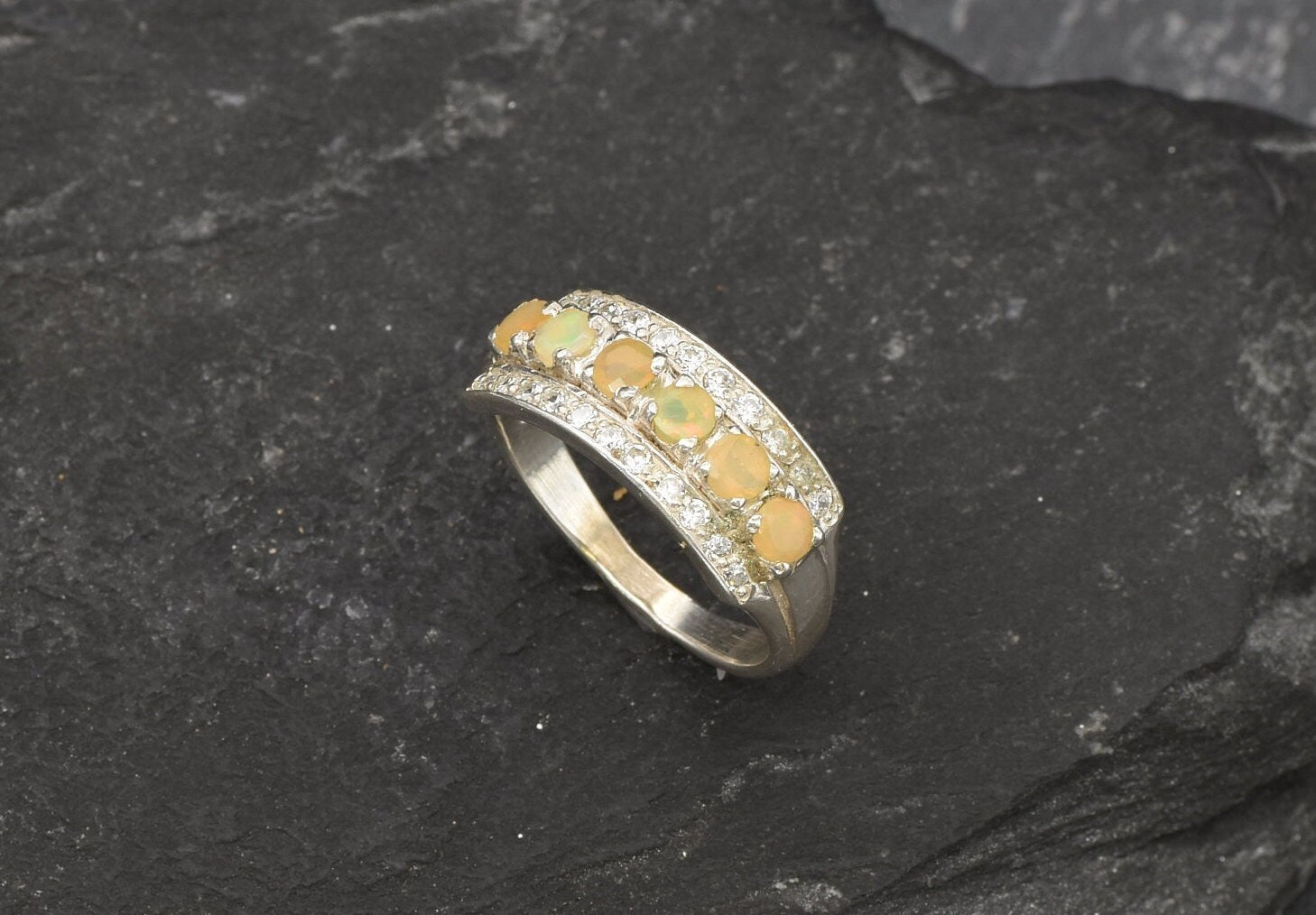 Opal Row Half Eternity Wide Ring in sterling silver featuring natural fire opals with flashes of fire colors, accented by CZ pave for a bold jewelry style. A meaningful October birthstone piece symbolizing balance and inspiration, making it a treasured gift idea. Perfect for weddings, anniversaries, cocktail events, and elegant evening occasions.