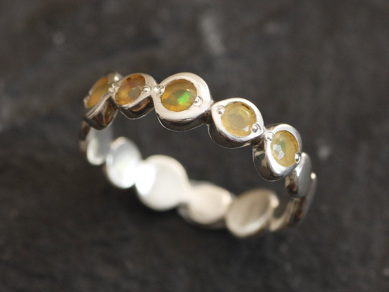 Yellow Ethiopian Fire Opal bezel tennis band eternity ring in sterling silver with diamond cut stones showing flashes of fire colors, a stylish jewelry design with bubble band details. Provides the benefit of a secure bezel setting and continuous gemstone glow, making it a meaningful October birthstone gift. Perfect for weddings, anniversaries, birthdays, and everyday wear.