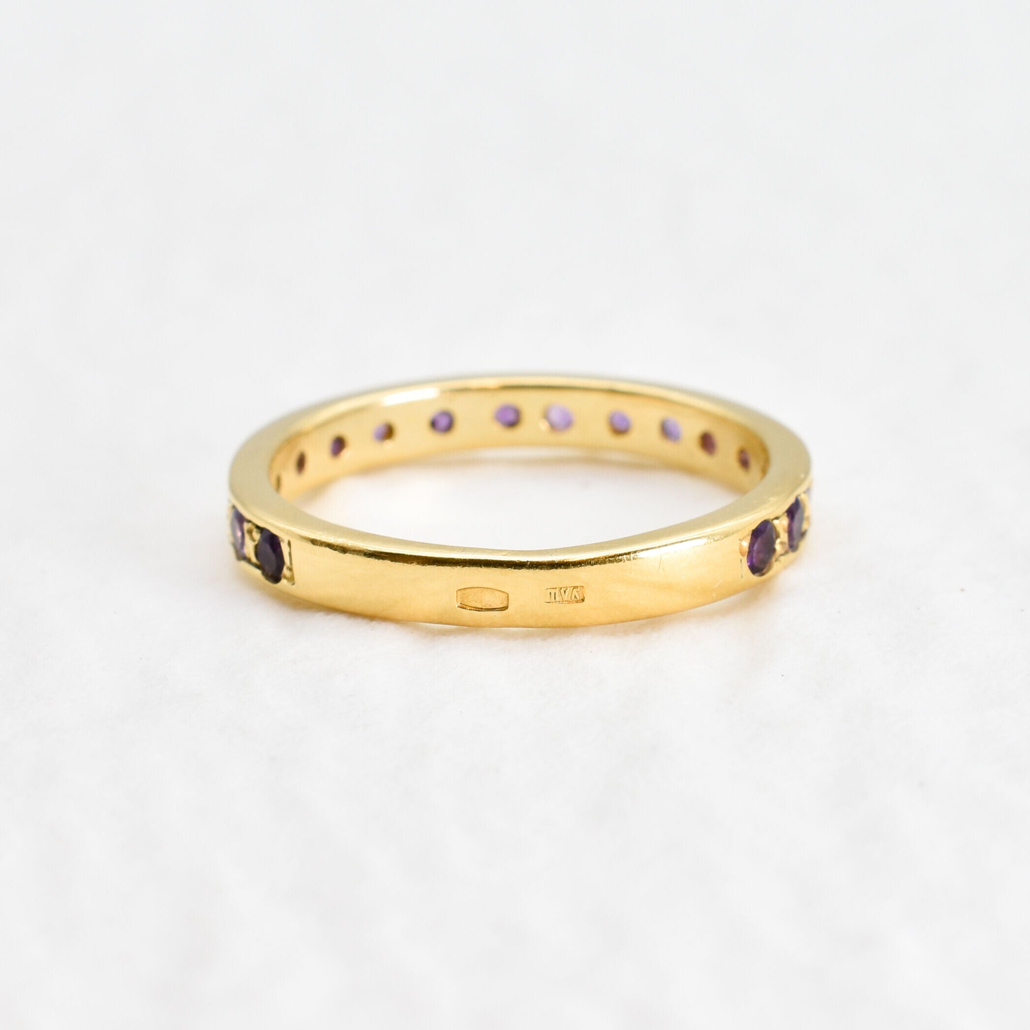 Side view of amethyst gold ring highlighting diamond cut stones and polished gold band