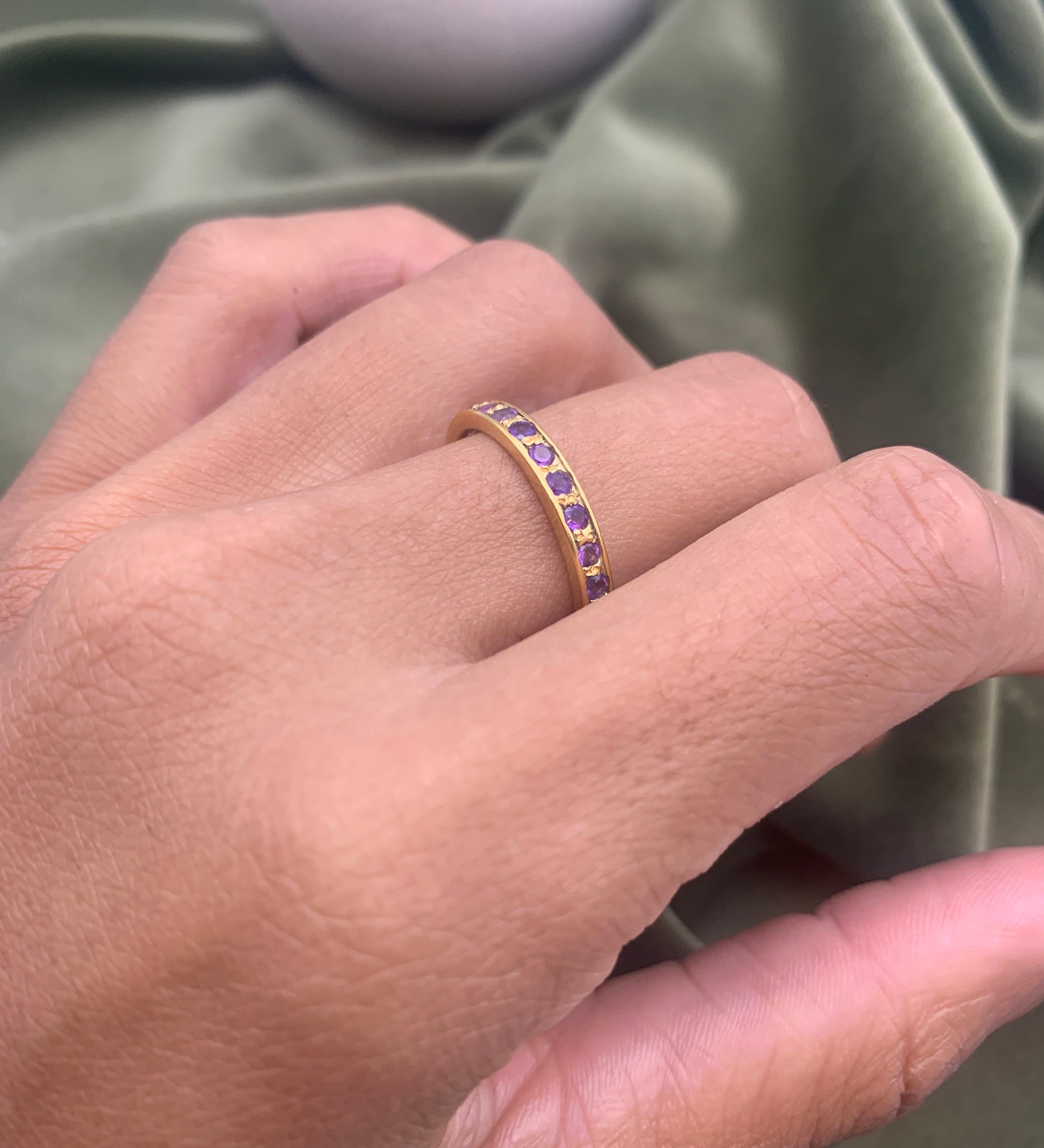 Woman wearing amethyst gold ring showing vibrant purple stones on finger