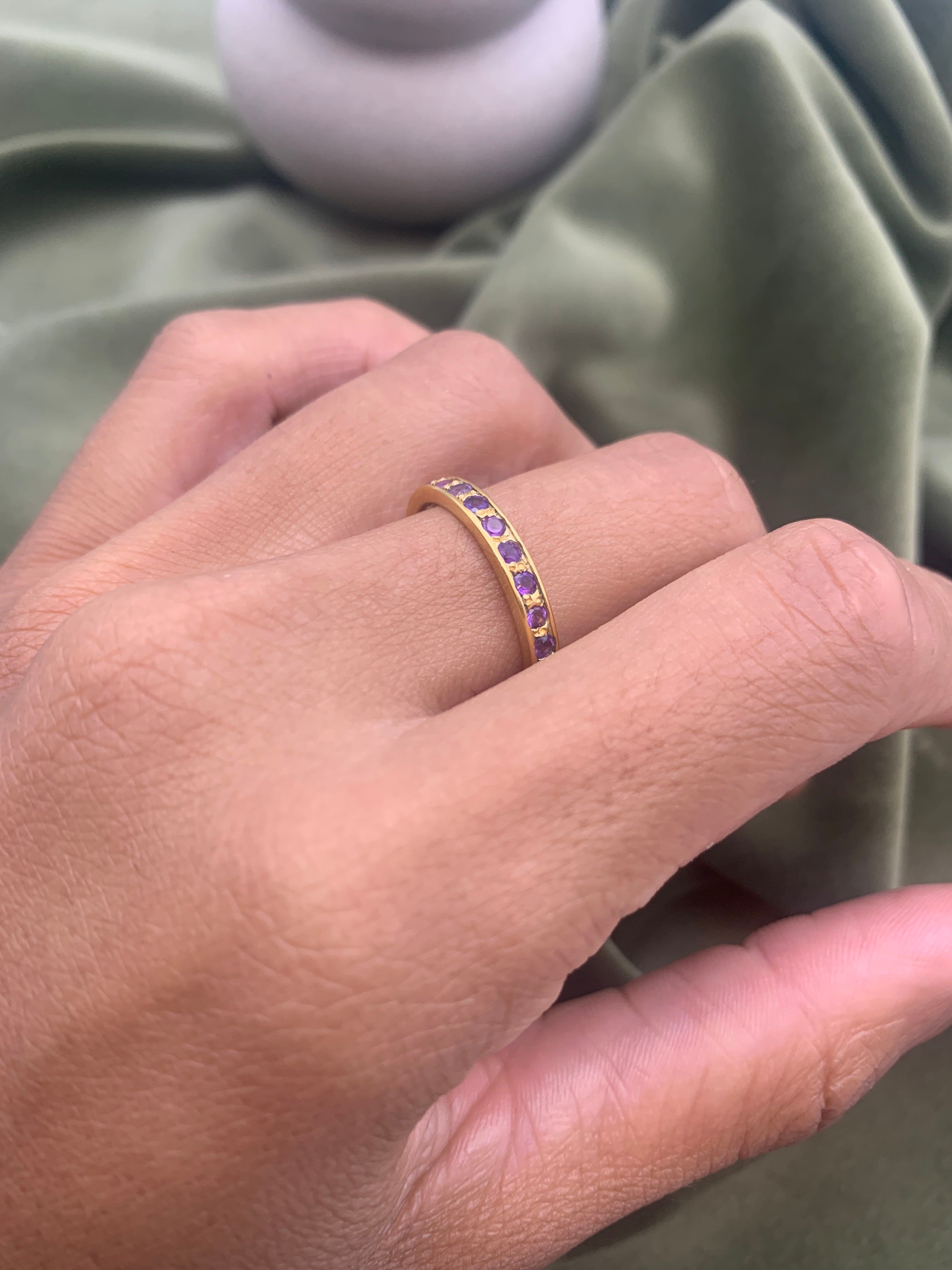 Woman wearing amethyst gold ring showing vibrant purple stones on finger