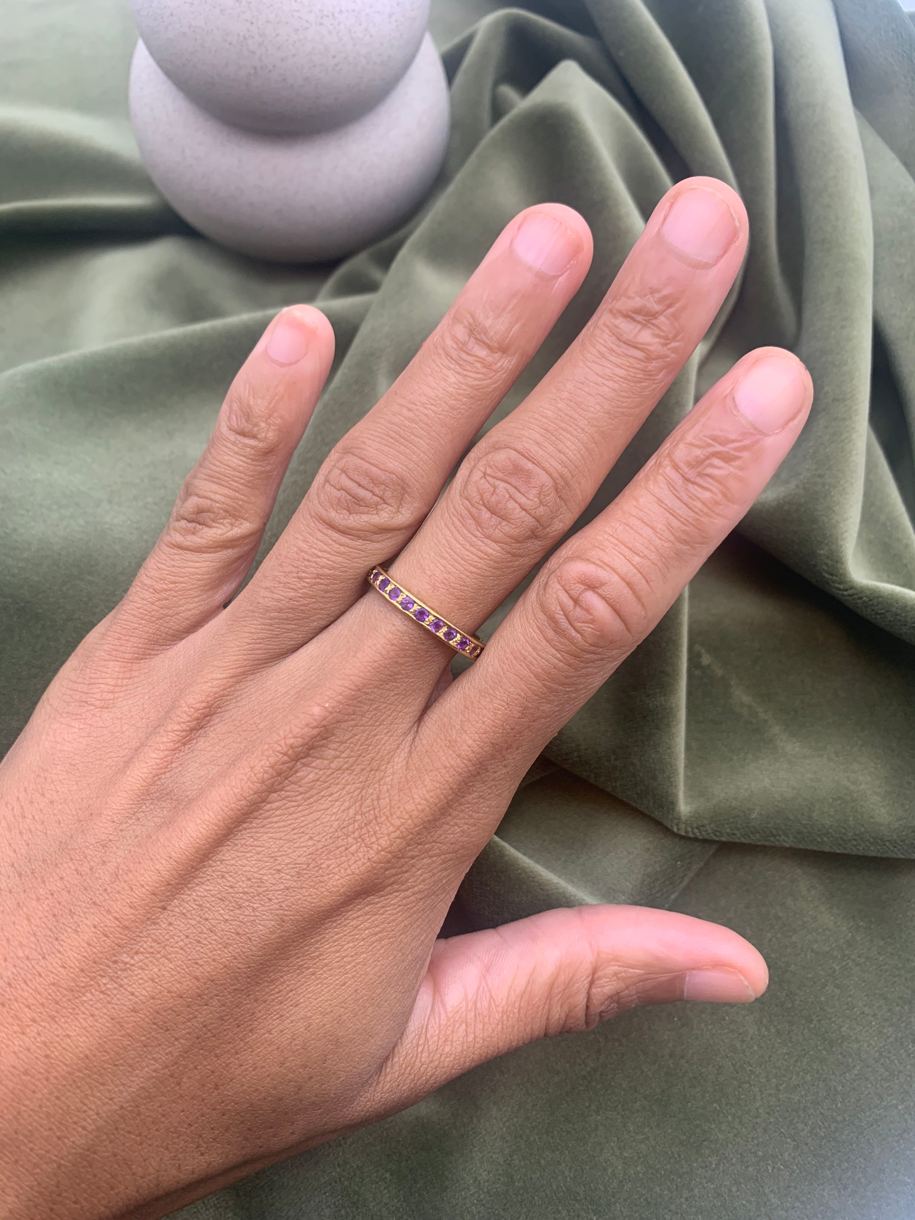 Close-up of amethyst gold ring worn on hand showing purple stones and elegant band design