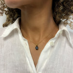 Woman in white linen shirt wearing natural black hematite necklace, set in gold vermeil over sterling silver. Black gemstone pendant that stands out and styles well with white and minimalist outfit. 