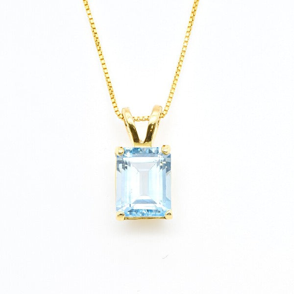 Blue topaz pendant with 10x8mm emerald cut gemstone set in polished gold, shown on white background