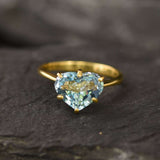 Front profile view of blue topaz heart gold ring highlighting gemstone brilliance and gold band craftsmanship