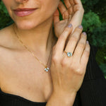 Woman modeling blue topaz heart gold ring paired with matching jewelry set