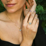 Woman modeling blue topaz heart gold ring paired with matching jewelry set